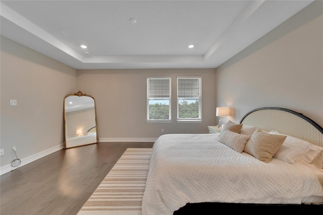 bedroom with a raised ceiling and dark hardwood / wood-style floors