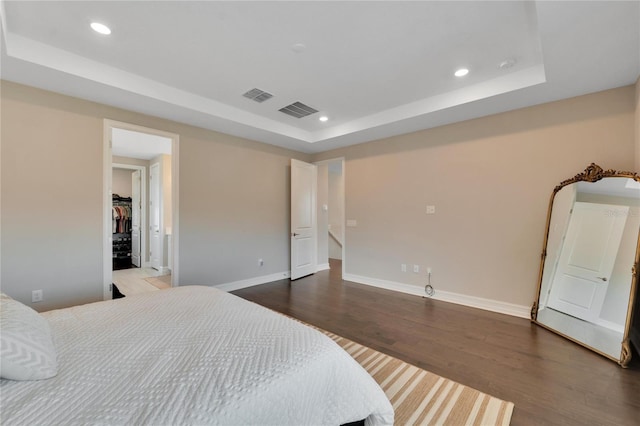 bedroom with wood-type flooring and a tray ceiling