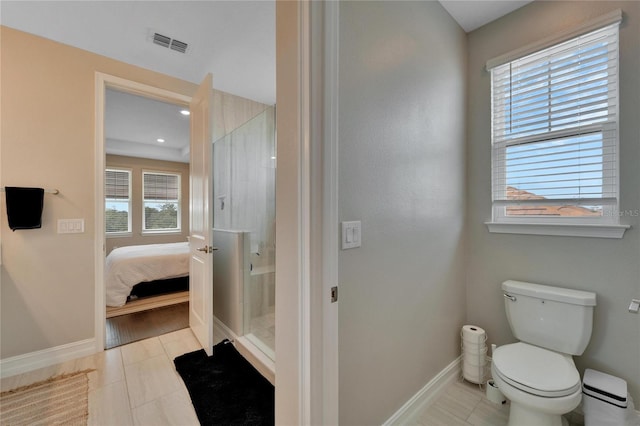 bathroom featuring tile patterned flooring, a shower with shower door, and toilet