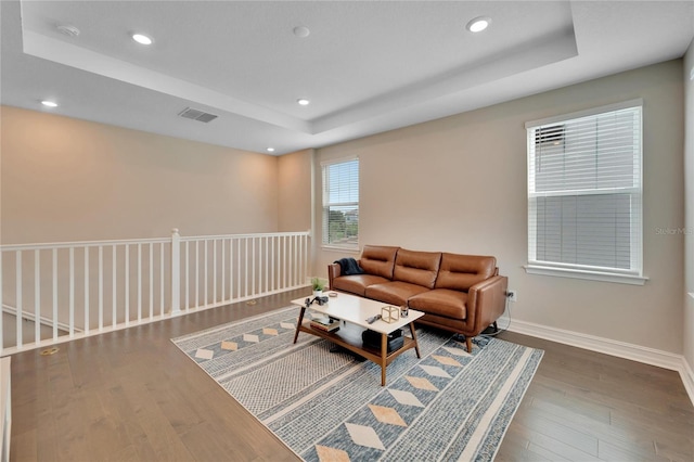 living room with wood-type flooring and a tray ceiling