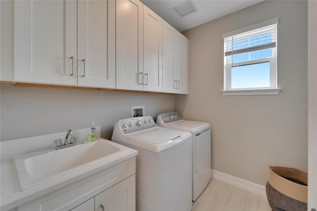 washroom featuring cabinets, sink, and washer and dryer