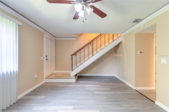 foyer with a textured ceiling, light hardwood / wood-style flooring, and ornamental molding