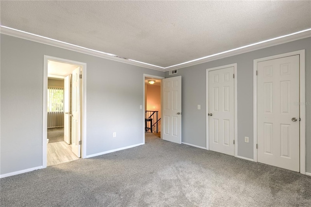 unfurnished bedroom with light colored carpet, a textured ceiling, and ornamental molding