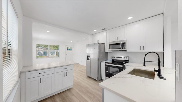 kitchen featuring light stone counters, white cabinets, sink, stainless steel appliances, and light hardwood / wood-style floors