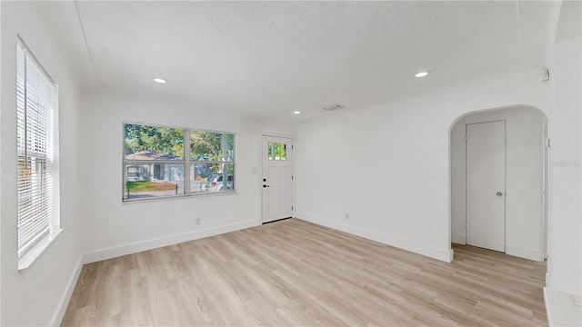 unfurnished room with a textured ceiling and light hardwood / wood-style floors