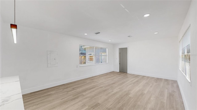 spare room with electric panel and light hardwood / wood-style flooring