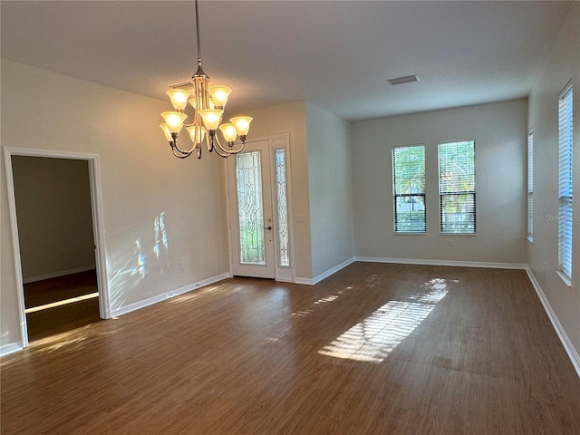 spare room featuring dark hardwood / wood-style floors and an inviting chandelier