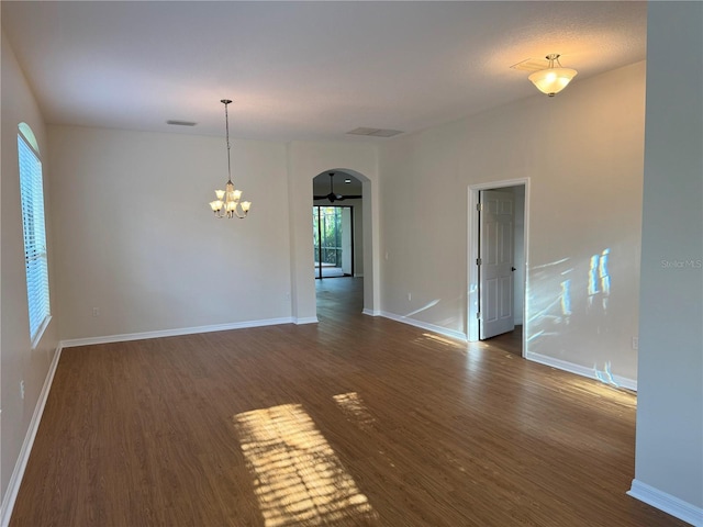 spare room with dark hardwood / wood-style floors and an inviting chandelier