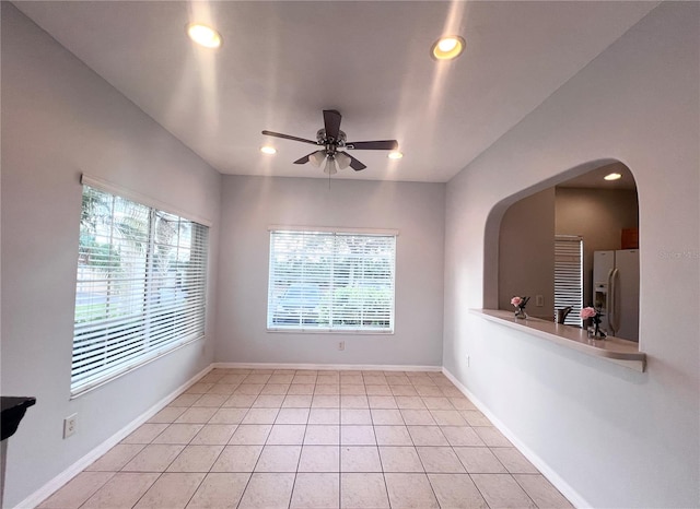 empty room with ceiling fan, light tile patterned floors, and a wealth of natural light