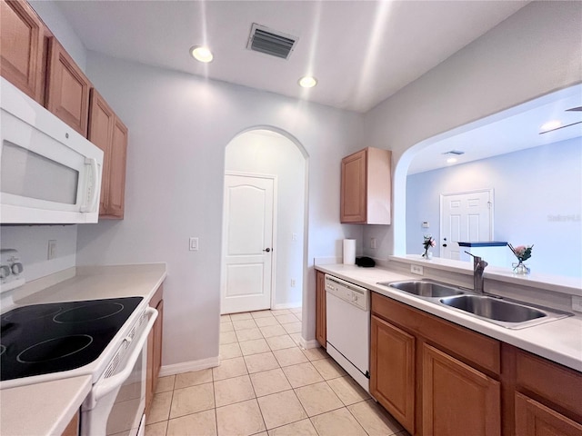 kitchen with white appliances, sink, and light tile patterned floors