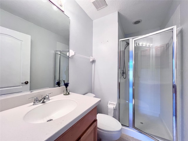 bathroom featuring vanity, toilet, a textured ceiling, walk in shower, and tile patterned flooring