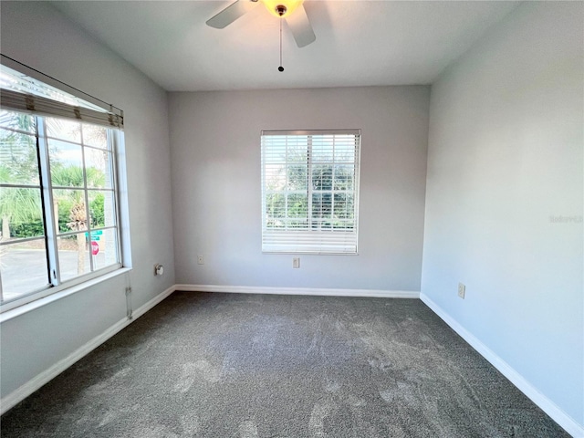 unfurnished room with ceiling fan, dark carpet, and a wealth of natural light