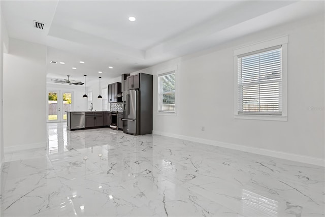 unfurnished living room featuring ceiling fan, a raised ceiling, and sink