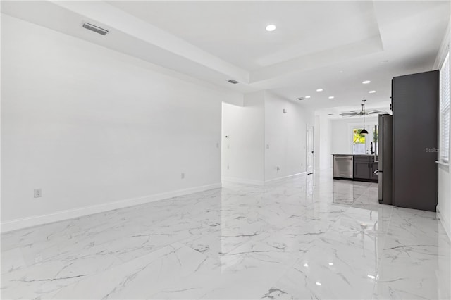 unfurnished living room featuring a tray ceiling and ceiling fan