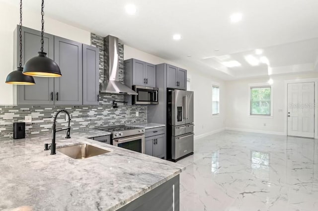 kitchen with light stone counters, sink, wall chimney exhaust hood, gray cabinetry, and appliances with stainless steel finishes