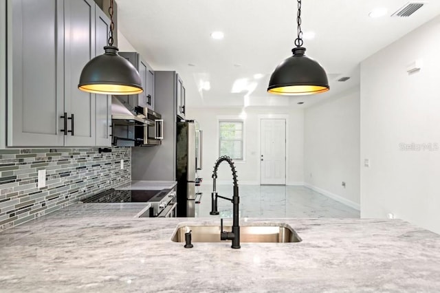 kitchen featuring gray cabinets, tasteful backsplash, sink, stainless steel appliances, and light stone countertops