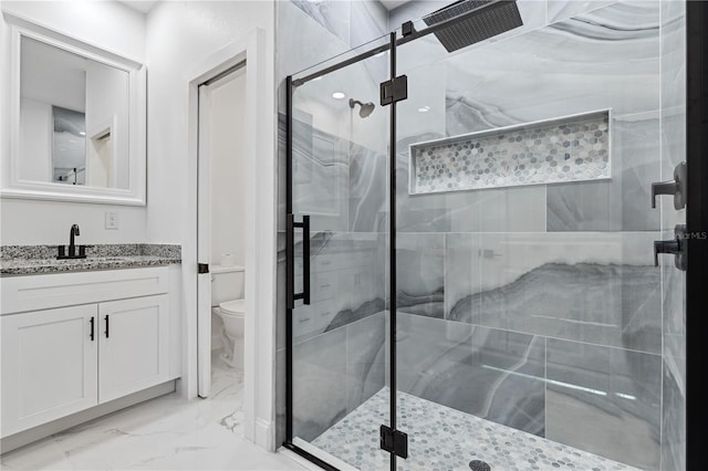 bathroom with vanity, a shower with shower door, and toilet