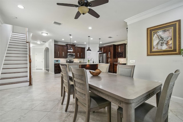 dining area with ceiling fan, light tile patterned floors, sink, and ornamental molding