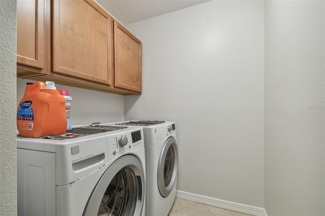 washroom with cabinets, light tile patterned flooring, and washer and clothes dryer