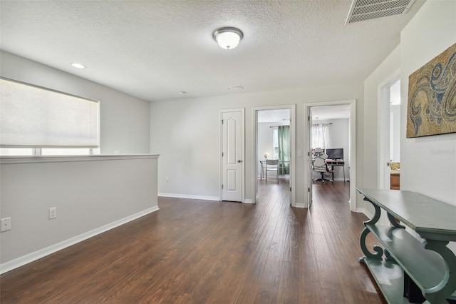 interior space with a textured ceiling and dark hardwood / wood-style flooring