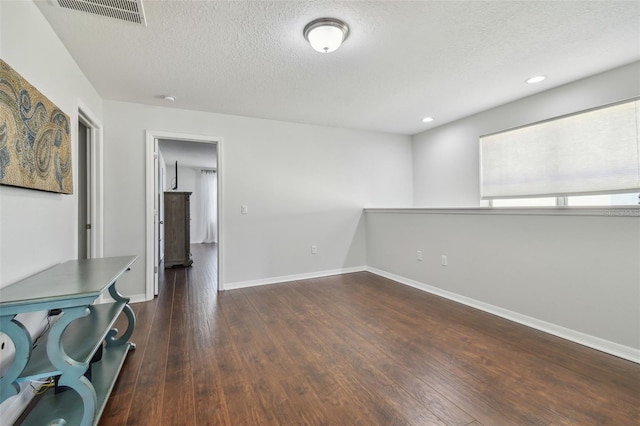 unfurnished room with a textured ceiling and dark wood-type flooring