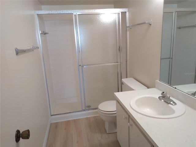 bathroom with hardwood / wood-style floors, walk in shower, vanity, and toilet