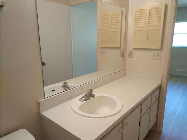 bathroom with wood-type flooring, vanity, and toilet