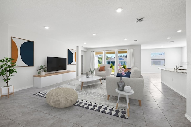 living room featuring a textured ceiling, sink, and light tile patterned floors