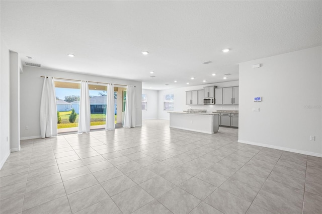 unfurnished living room with a textured ceiling and light tile patterned floors