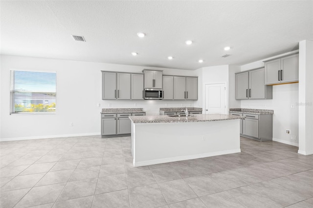 kitchen featuring a center island with sink and gray cabinets