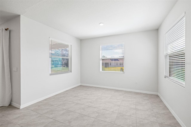 tiled spare room featuring a textured ceiling and plenty of natural light