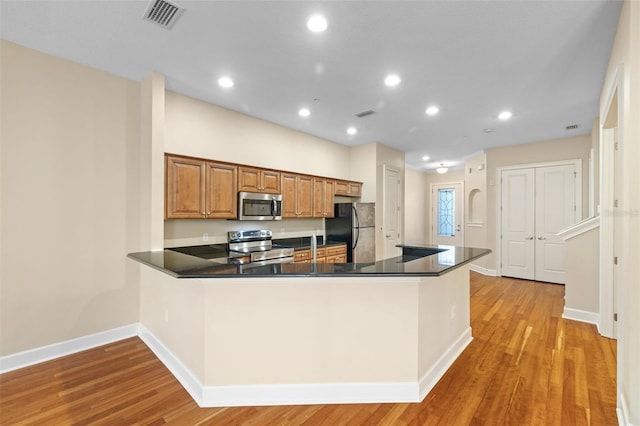 kitchen featuring kitchen peninsula, stainless steel appliances, and light hardwood / wood-style floors