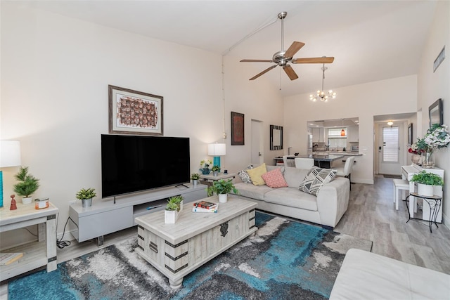 living room with ceiling fan, light wood-type flooring, and high vaulted ceiling