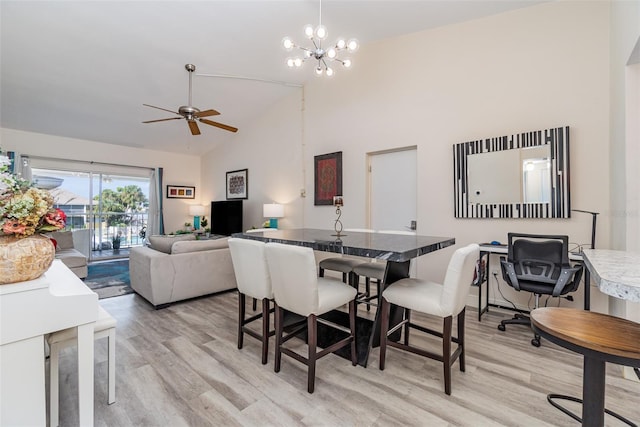 dining area with ceiling fan with notable chandelier, light hardwood / wood-style floors, and high vaulted ceiling