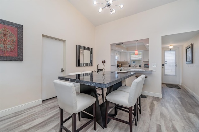 dining space with a raised ceiling, light hardwood / wood-style floors, and a chandelier