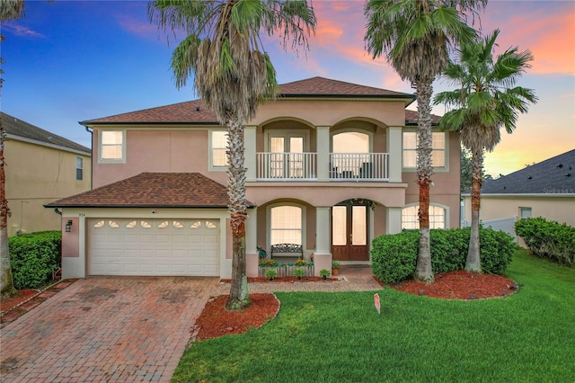 mediterranean / spanish-style house with a balcony, a garage, and a yard