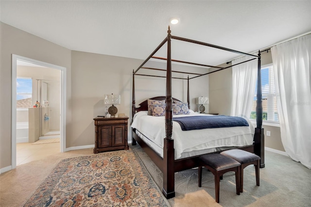 carpeted bedroom with ensuite bathroom and multiple windows