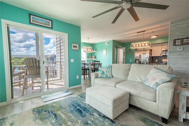 living room with light hardwood / wood-style flooring, ceiling fan, and sink