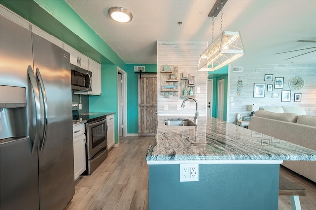 kitchen featuring hanging light fixtures, sink, stainless steel appliances, and white cabinets