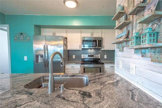 kitchen featuring white cabinetry, stainless steel appliances, a textured ceiling, carpet, and sink