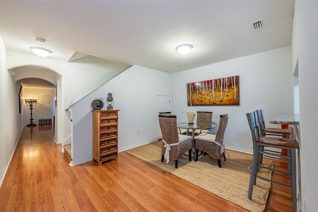 dining space with light wood-type flooring and a textured ceiling