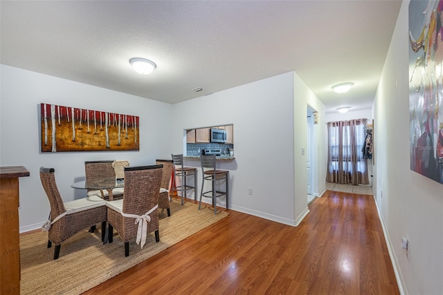 dining space with wood-type flooring and a textured ceiling