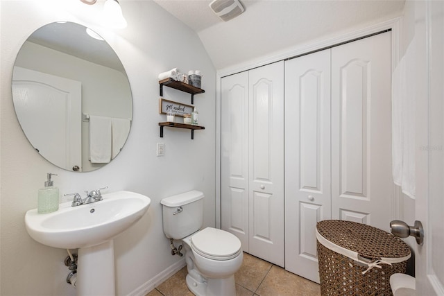 bathroom with vaulted ceiling, toilet, and tile patterned floors