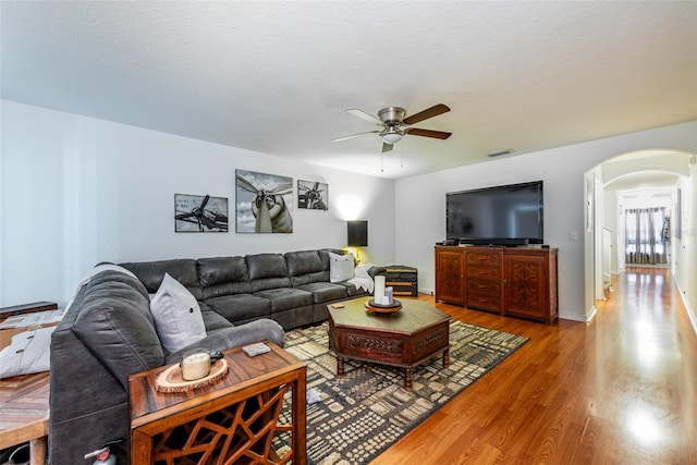 living room with a textured ceiling, hardwood / wood-style floors, and ceiling fan