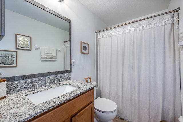 bathroom with a textured ceiling, curtained shower, vanity, and toilet