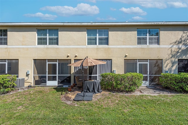 rear view of property with a sunroom, a lawn, and central AC