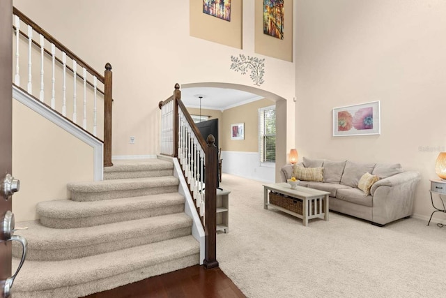 staircase featuring crown molding, hardwood / wood-style floors, and a high ceiling