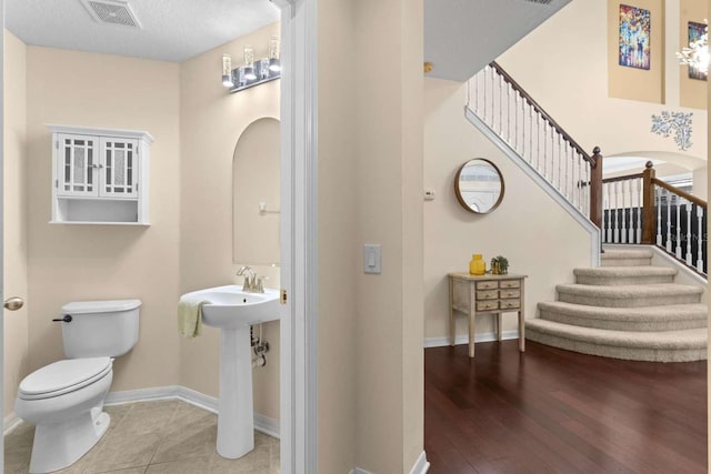 bathroom with a textured ceiling, hardwood / wood-style flooring, and toilet