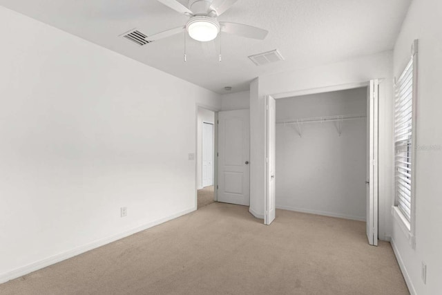 unfurnished bedroom with ceiling fan, a closet, light carpet, and multiple windows