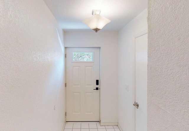 doorway featuring a textured ceiling and light tile patterned floors